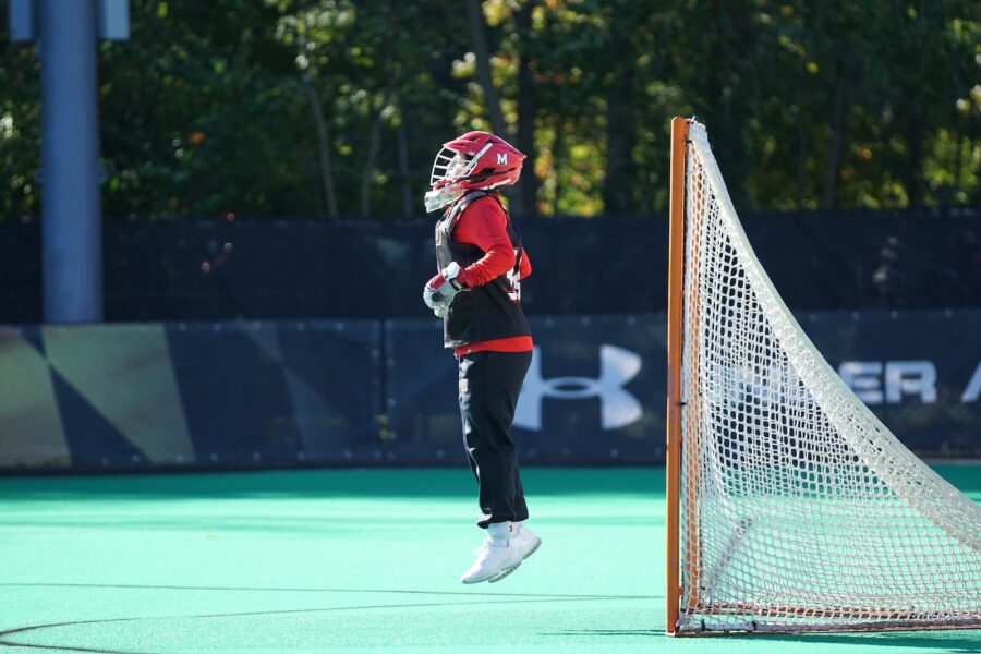 person jumping wearing red and white head gear in front of net goal